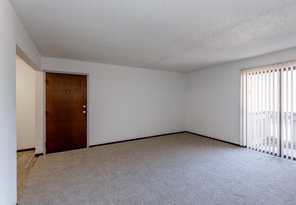 an empty bedroom with a door leading to a balcony