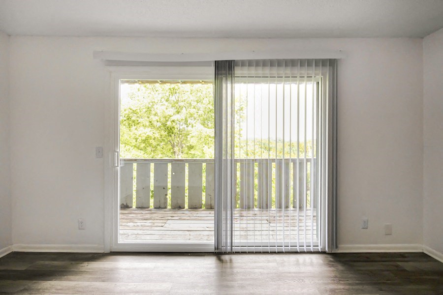 an empty living room with sliding glass doors and a balcony