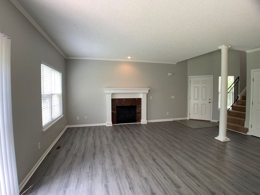 an empty living room with a fireplace and wooden floors