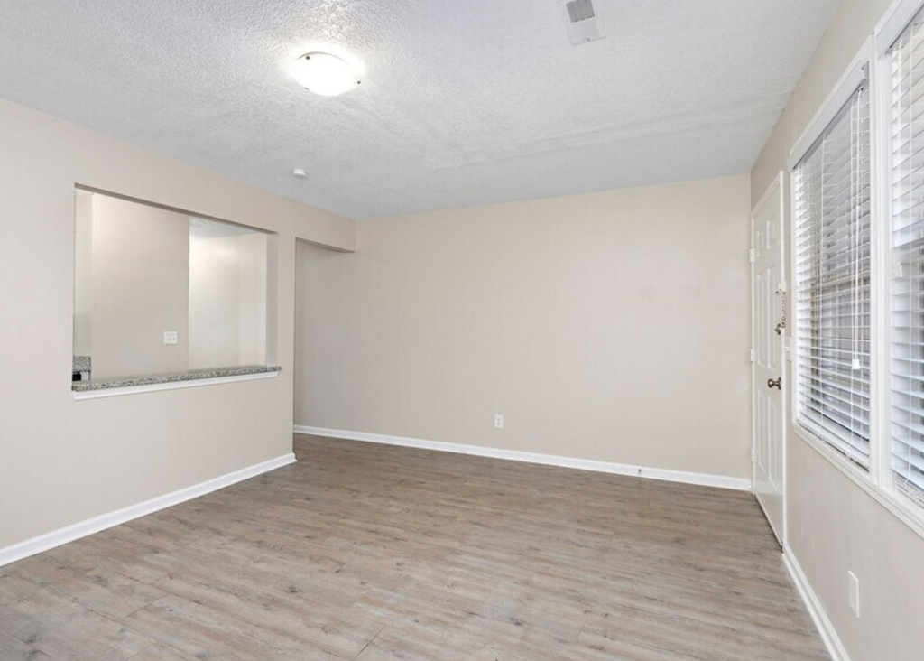 the spacious living room with a large window and white walls