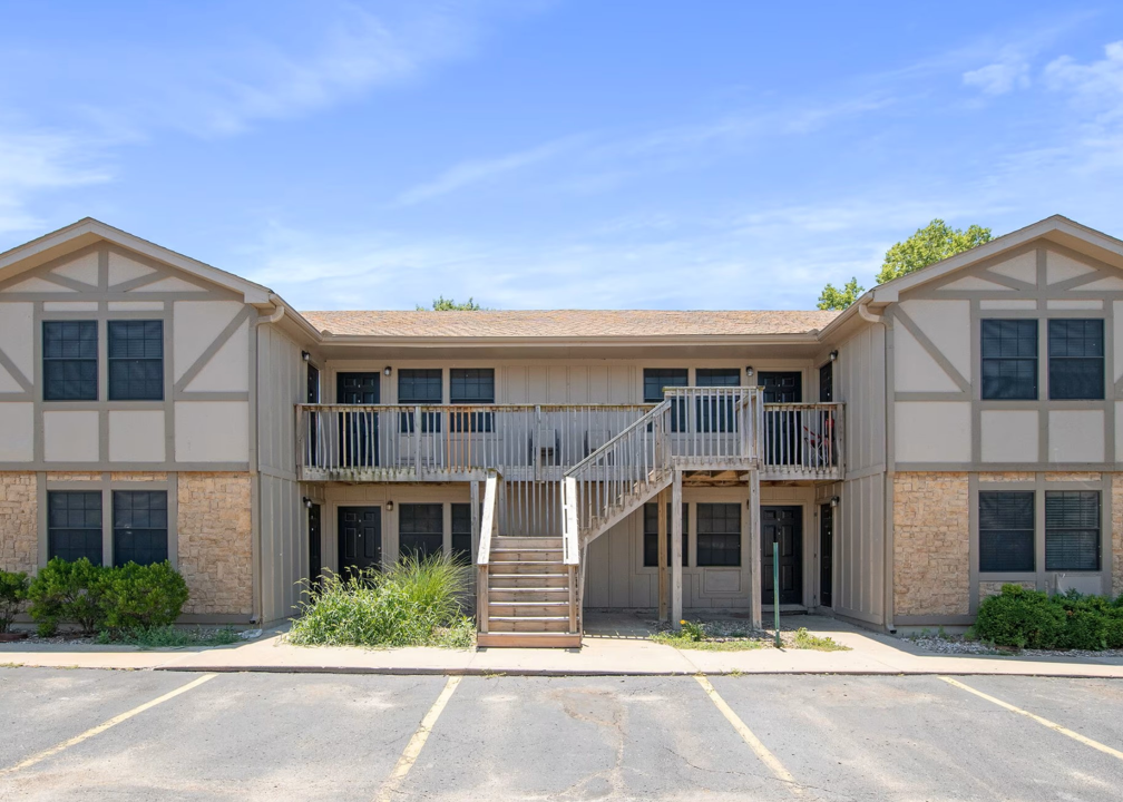 the exterior of an apartment building with stairs and a balcony