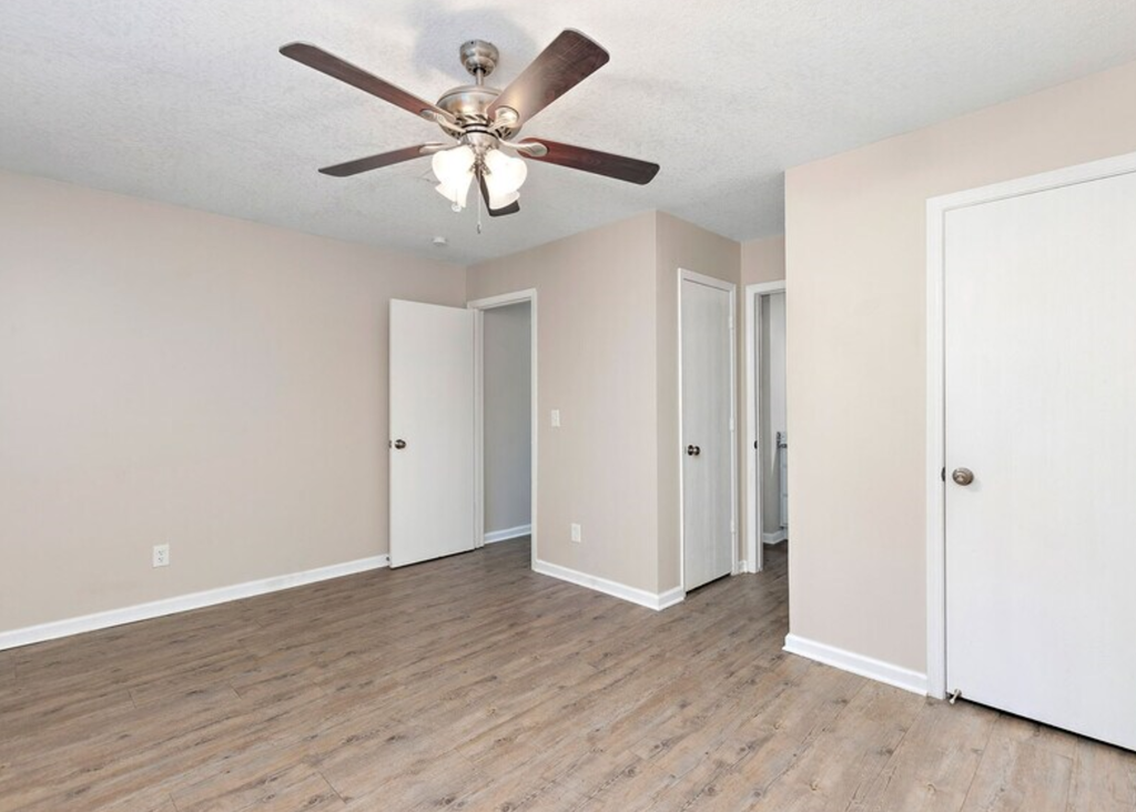 an empty living room with a ceiling fan
