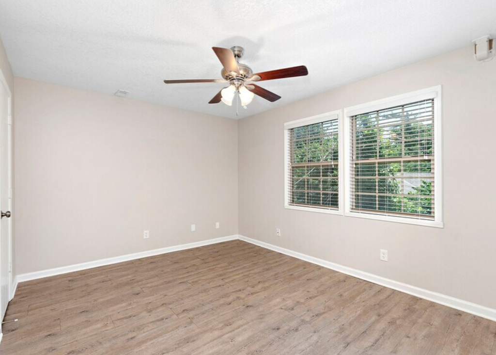 an empty living room with a ceiling fan and a window