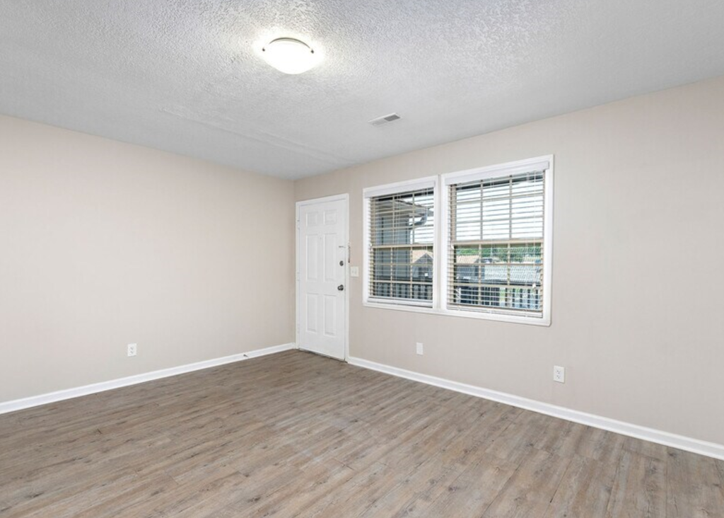 an empty living room with a window and a door