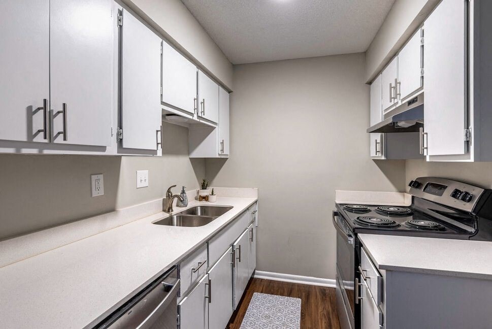 an empty kitchen with white cabinets and appliances and a sink
