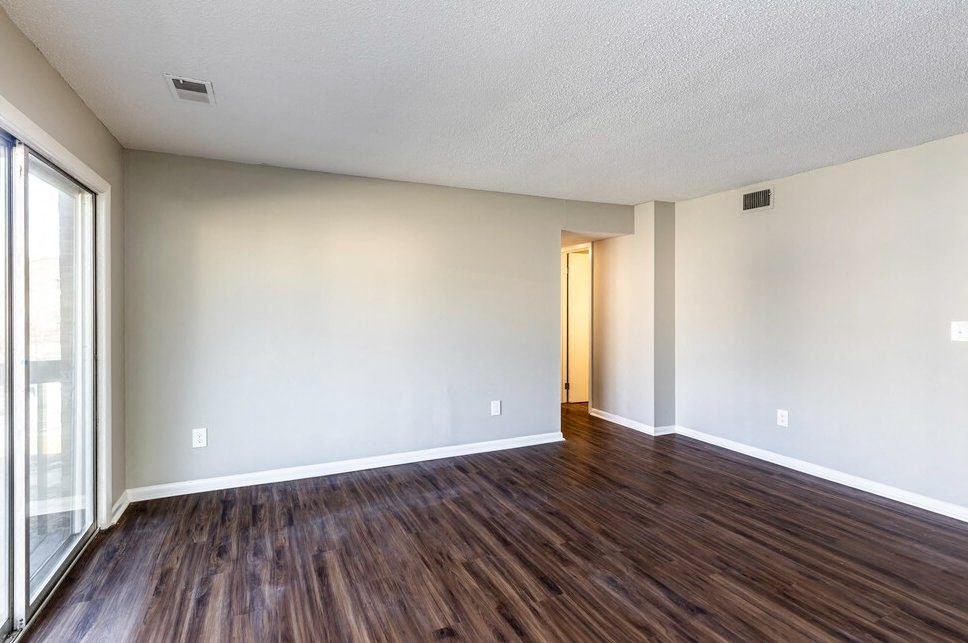 an empty living room with wood floors and white walls
