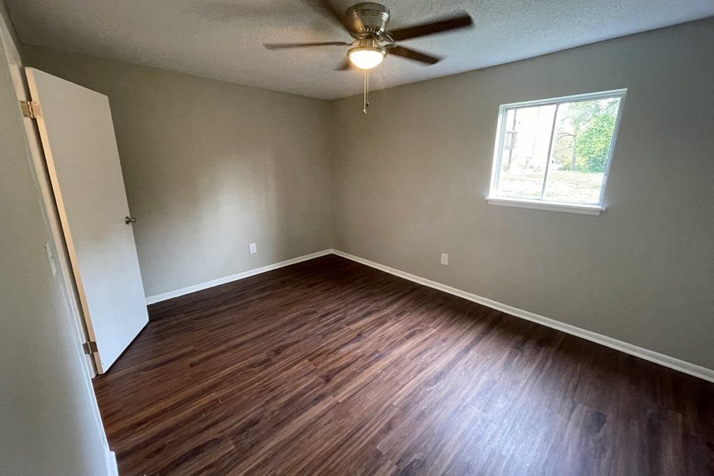 an empty room with wooden floors and a ceiling fan