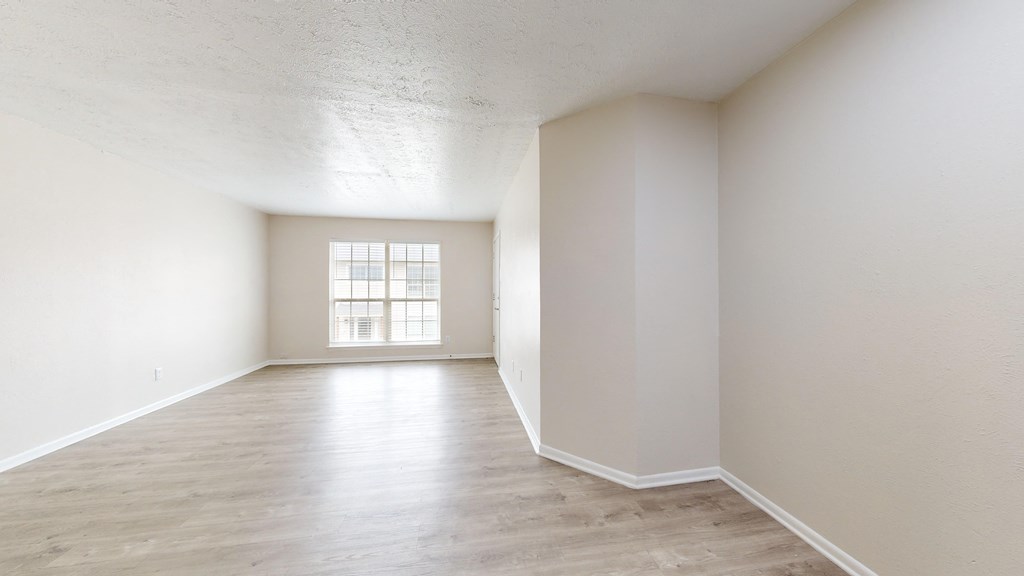 an empty living room with white walls and a window