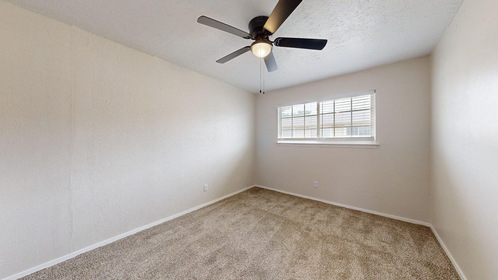 an empty room with a ceiling fan and a window