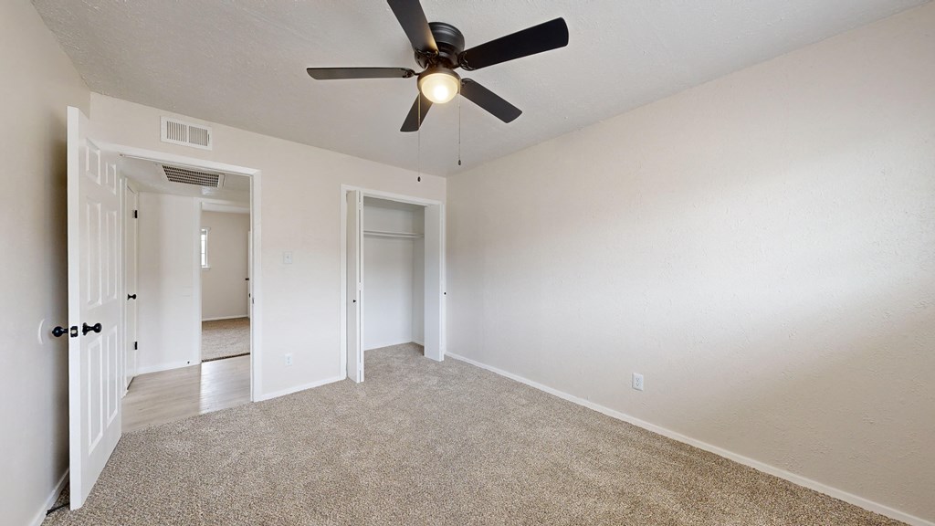 an empty living room with a ceiling fan
