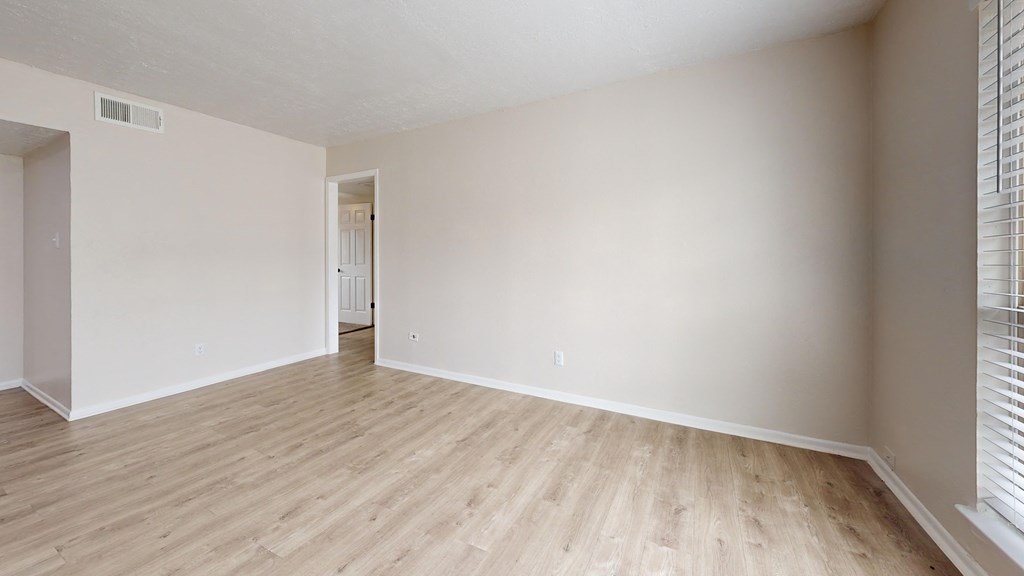 an empty living room with wood flooring and white walls