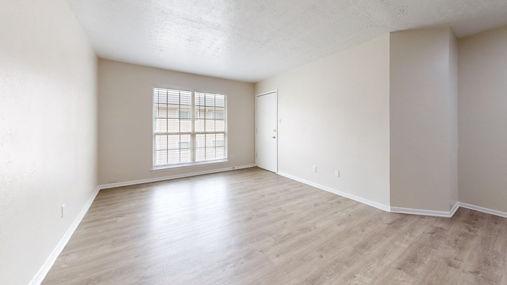 an empty living room with hardwood flooring and a window