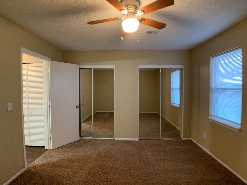 bedroom with ceiling fan and closets