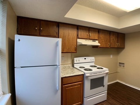 a kitchen with white appliances and wooden cabinets and a refrigerator