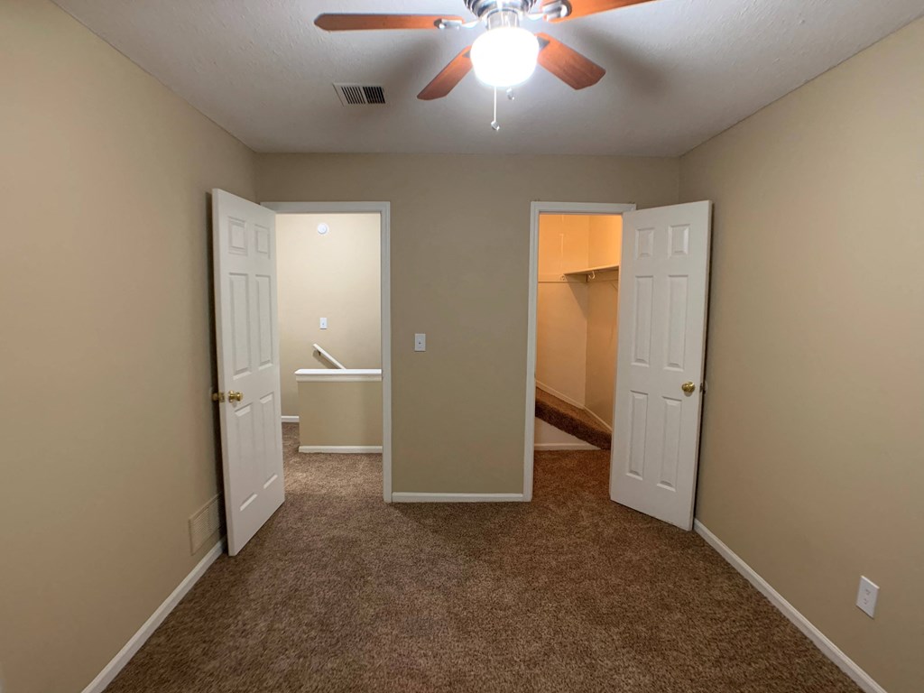 large carpeted bedroom with closet and ceiling fan