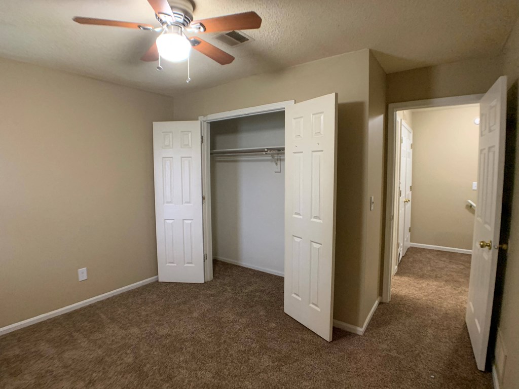 large carpeted bedroom with closet and ceiling fan