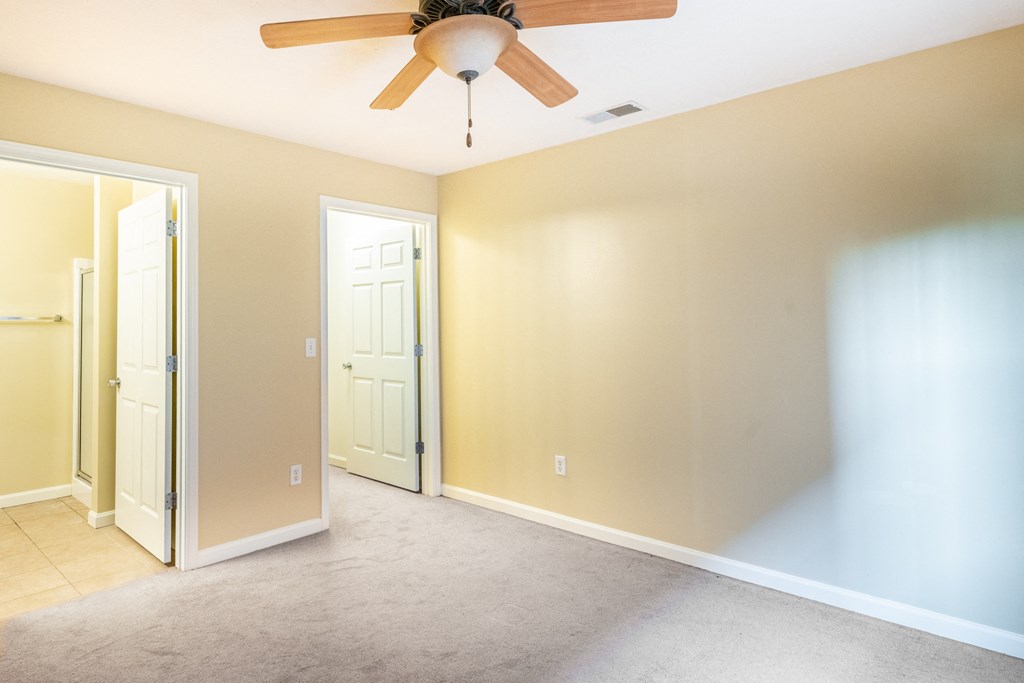Photo of carpeted bedroom with ceiling fan and view of closet  in Peoria.