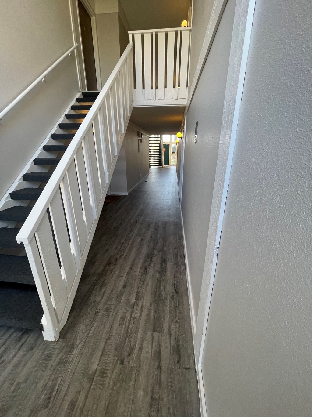 a look down the hallway of a house with hardwood floors and a staircase