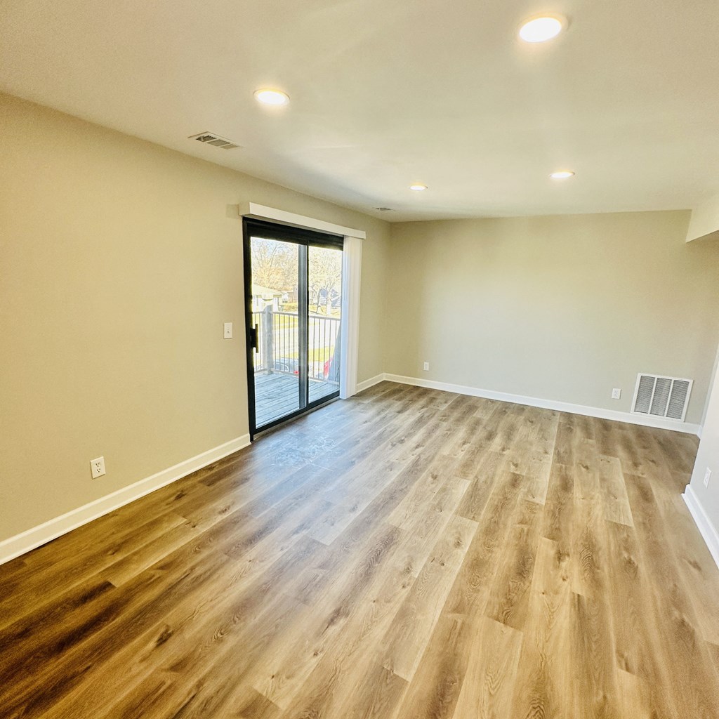 an empty living room with wood floors and a sliding glass door