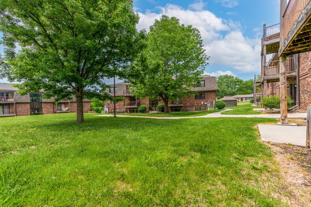 a grassy area with trees and buildings in the background