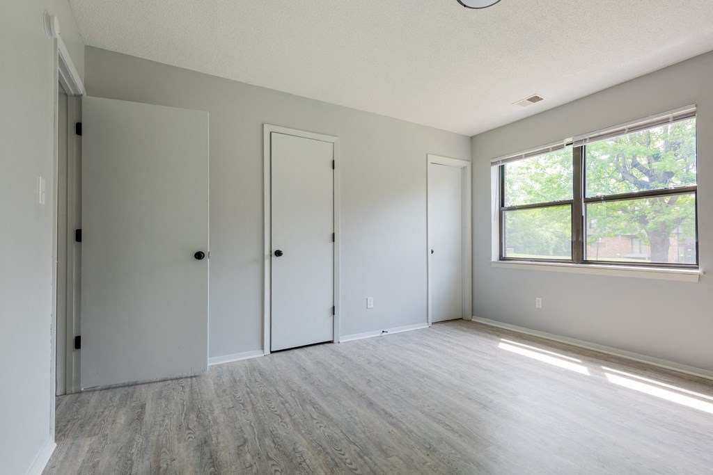 an empty bedroom with a large window and white walls