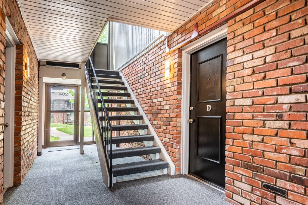 the front door of a brick building with a staircase leading up to it