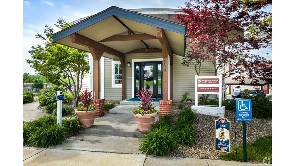 a tan building with a blue roof with a handicap sign in front of it