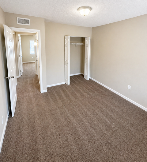 A room with carpeted floor and two open doors.