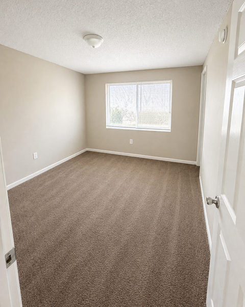 A room with a carpeted floor and a window.