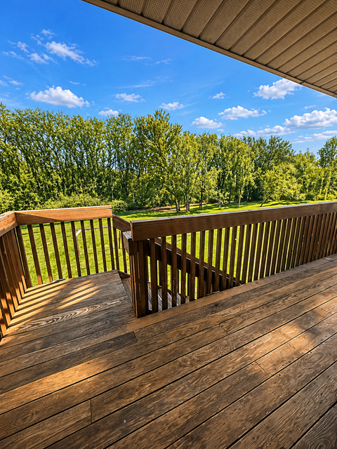 A wooden deck overlooks a grassy area with trees.