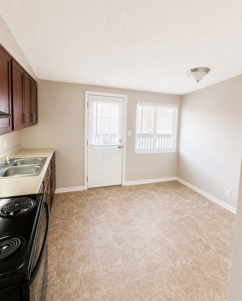 A kitchen with a black stove top oven and a white door.