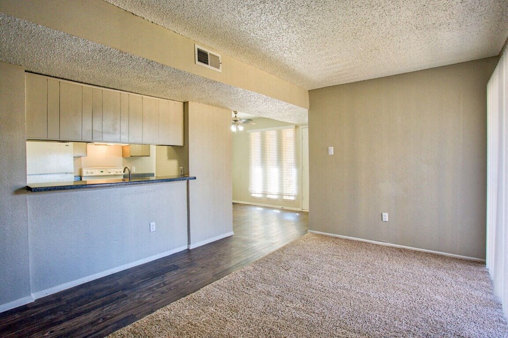 an empty living room with a kitchen and a counter top