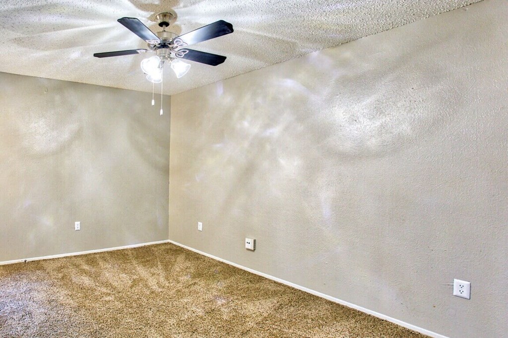 an empty room with a ceiling fan and carpet