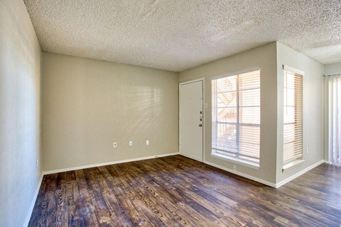 an empty living room with hard wood floors and a window
