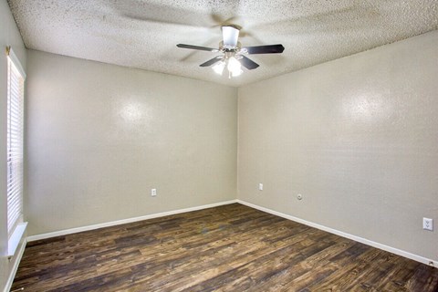 an empty living room with a ceiling fan and wood flooring