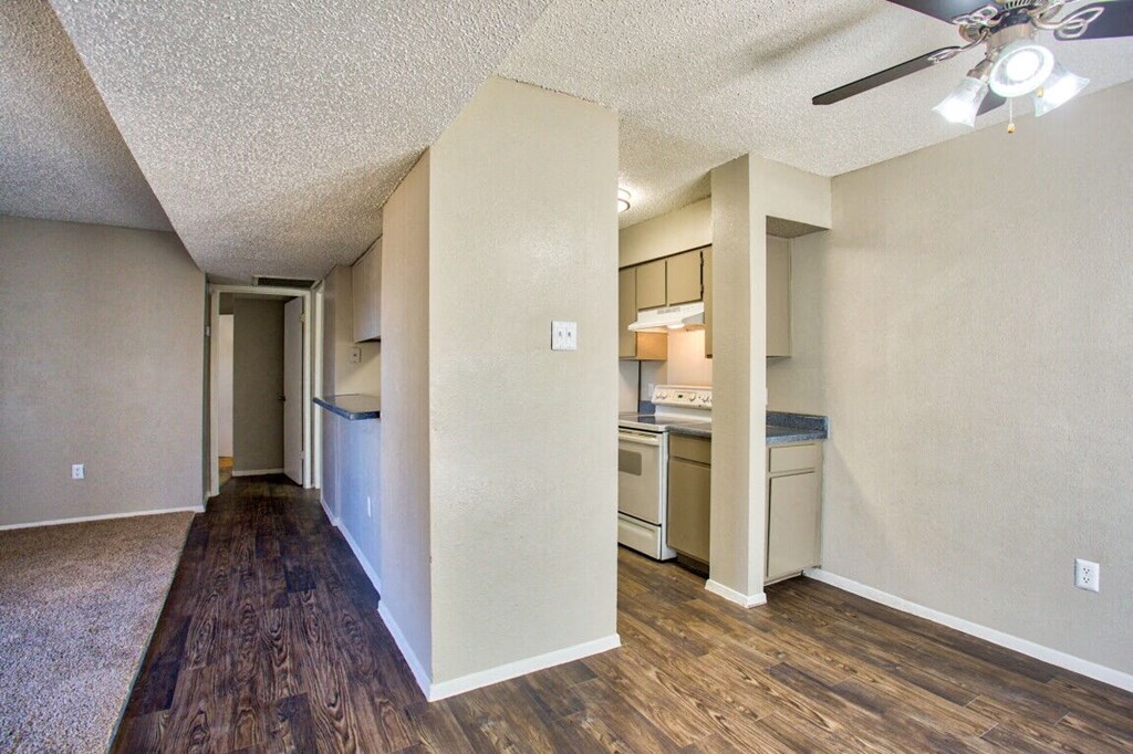 the living room and kitchen of an apartment with a hard wood floor