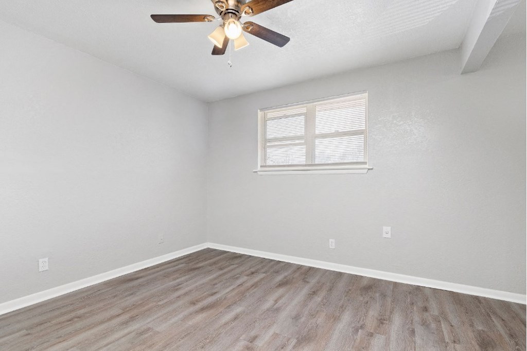 large room with plank flooring and ceiling fan