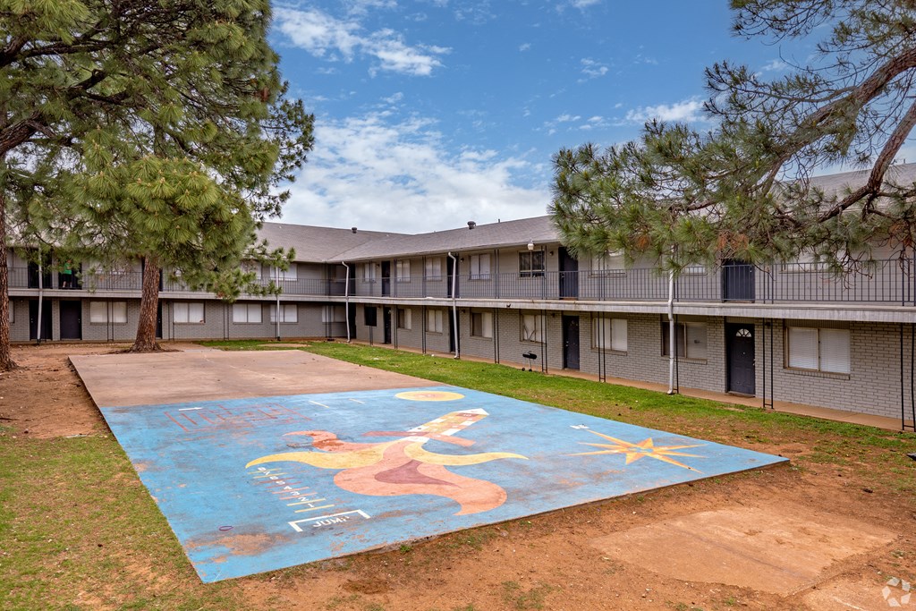 A mural of a woman is painted on a concrete surface in front of apartment buildings.