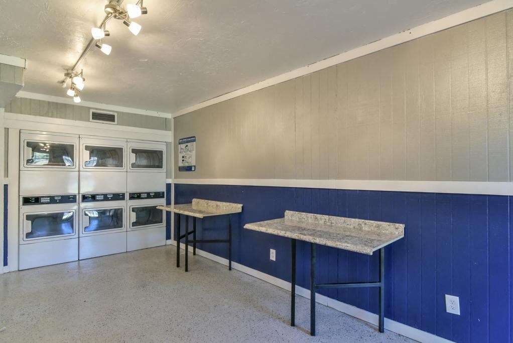 a laundry room with two tables and two refrigerators