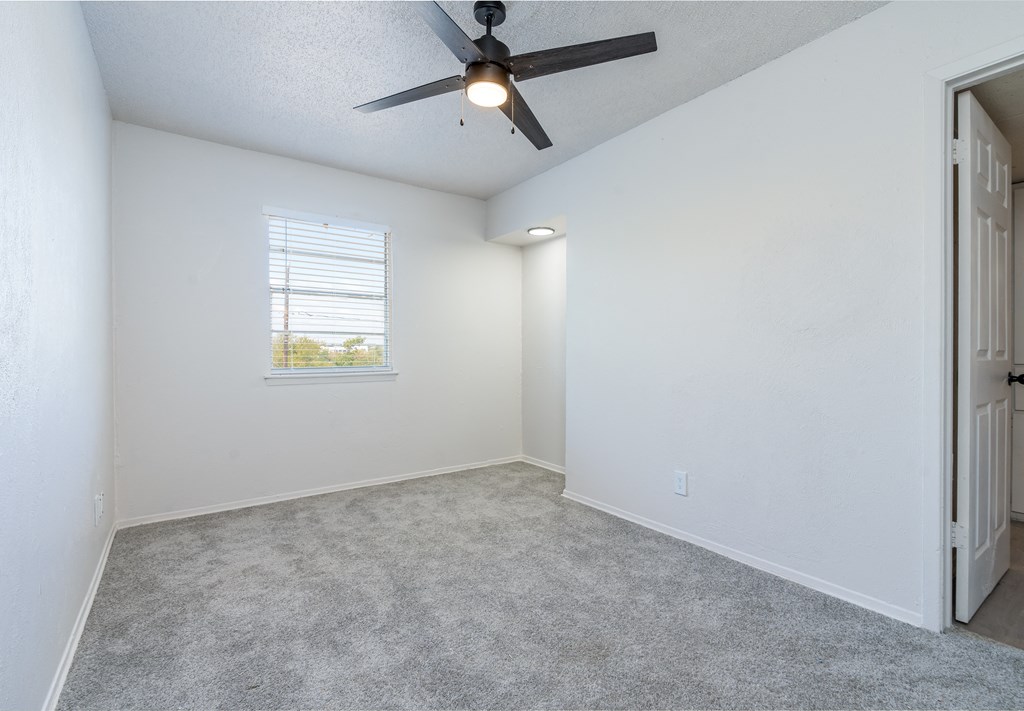 an empty room with a ceiling fan and a window