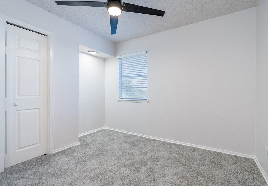 an empty room with white walls and a ceiling fan