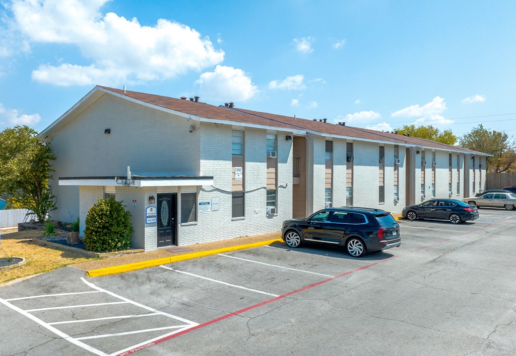 a white building with cars parked in a parking lot