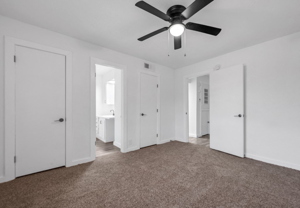 an empty living room with white walls and a ceiling fan
