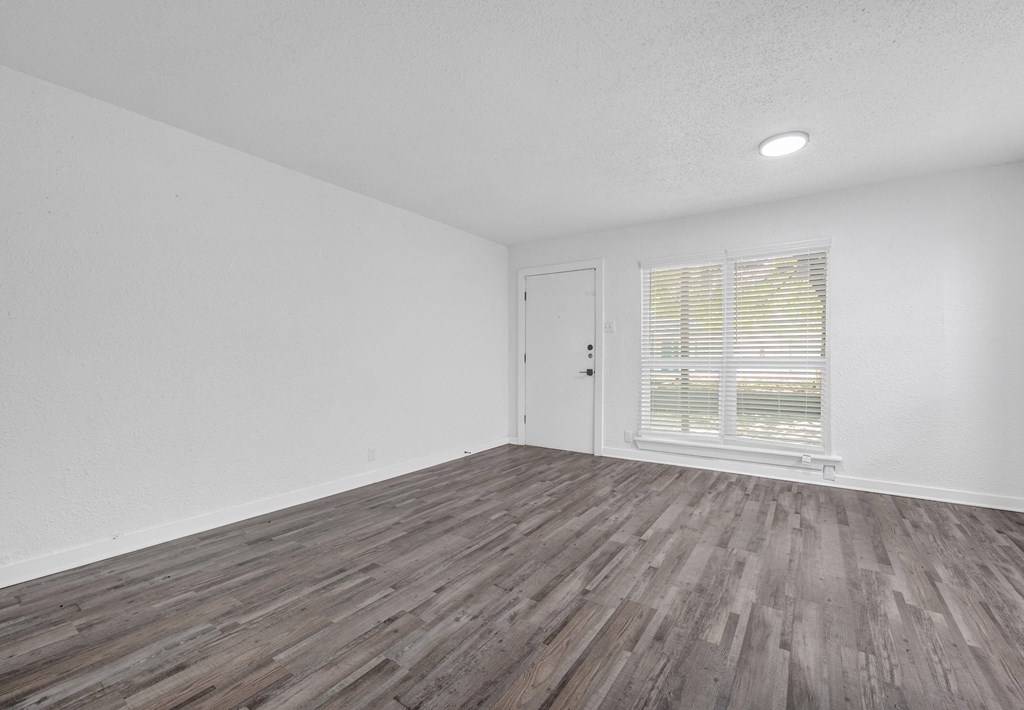 the living room of our studio apartment atrium with wood flooring and a window