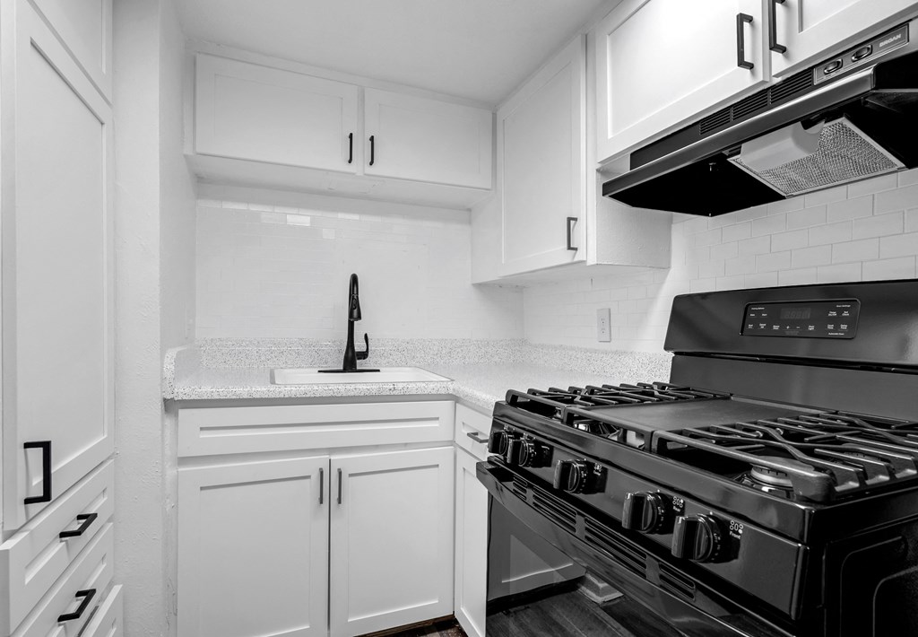 a kitchen with white cabinets and a stove and a sink