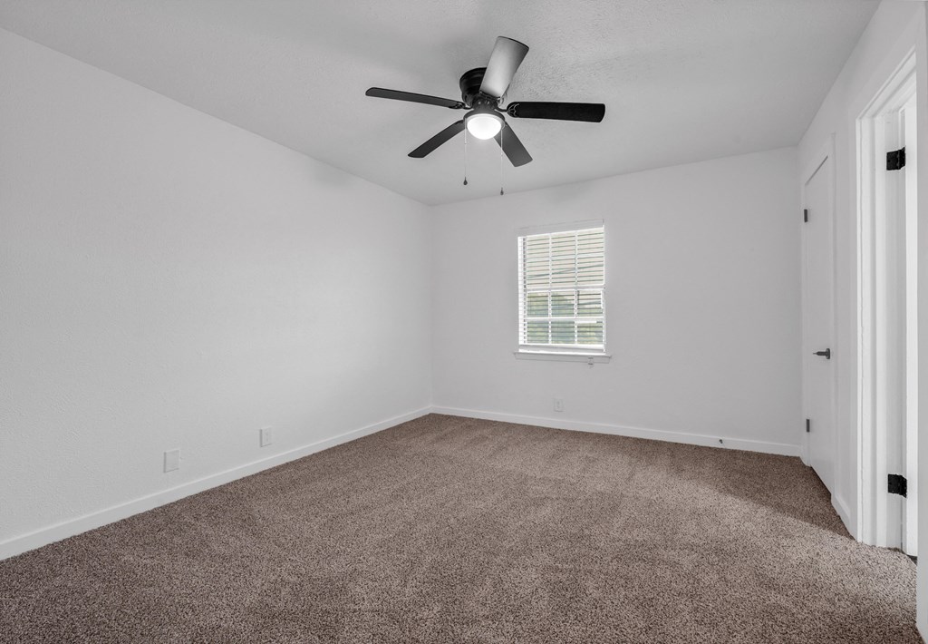 an empty room with a ceiling fan and carpet