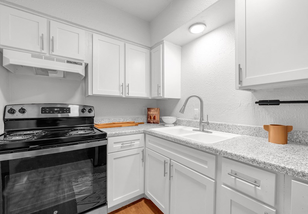 a kitchen with white cabinets and a stove and a sink