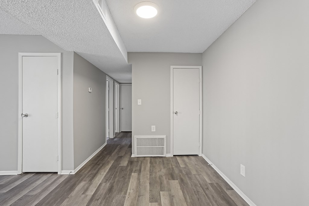 the spacious living room and hallway of a manufactured home with white walls and wood floors