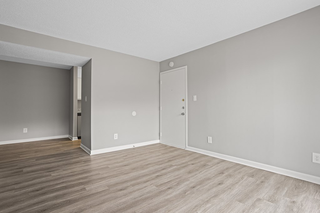 an empty living room with wood floors and grey walls