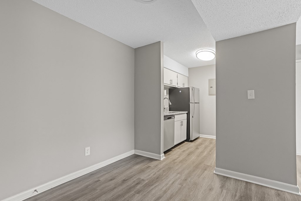 the living room and kitchen of an apartment with a refrigerator and stove